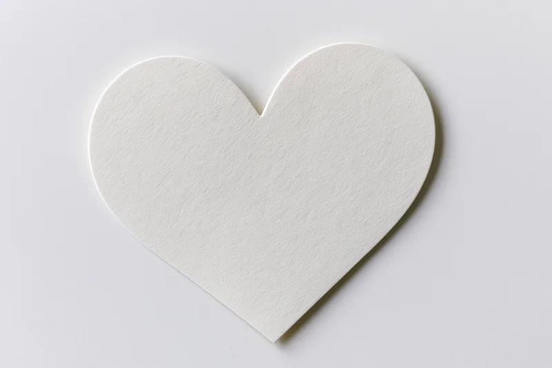 White heart-shaped paper cutout lying flat on a plain white surface