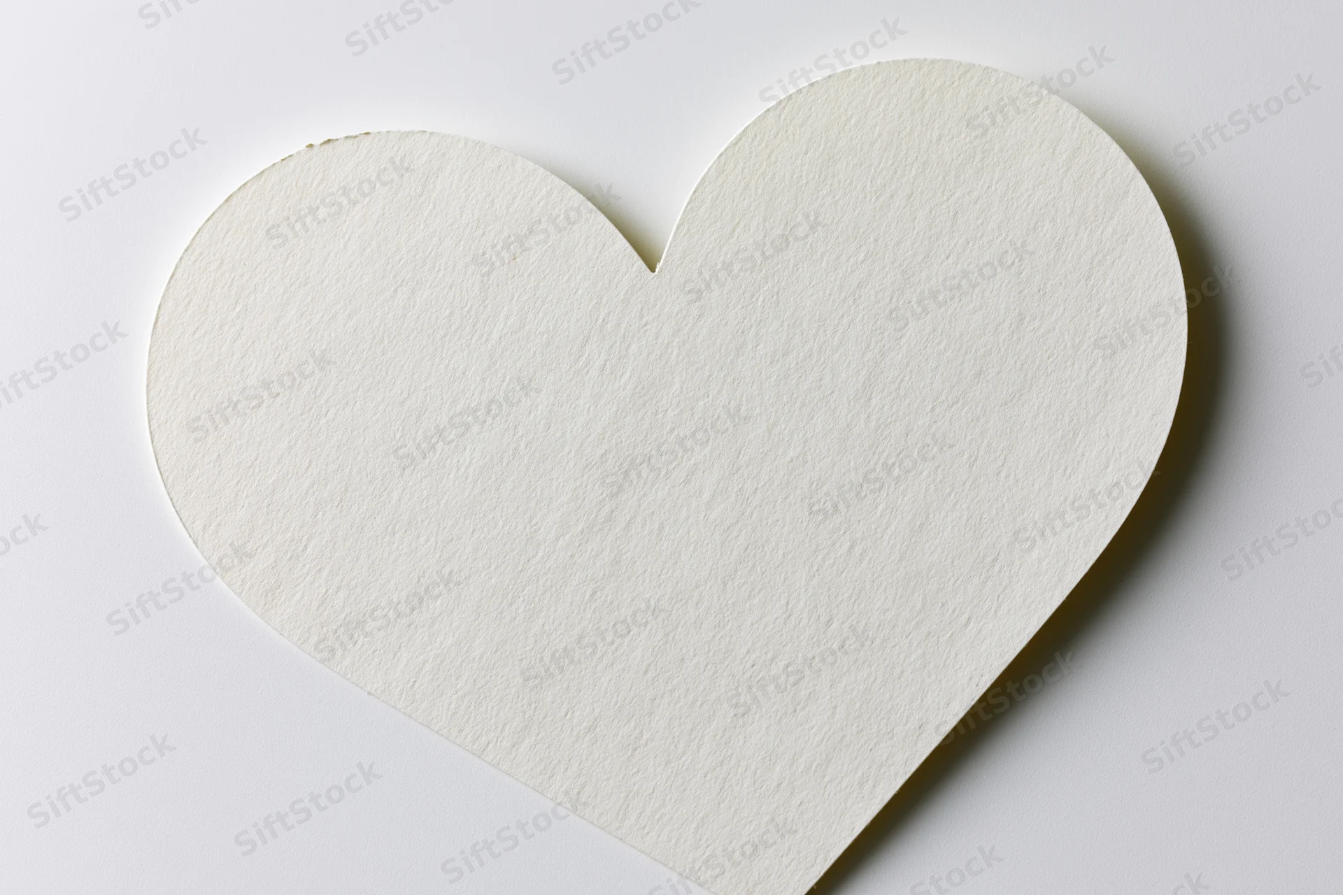 Heart-shaped paper cutout lying flat on white surface