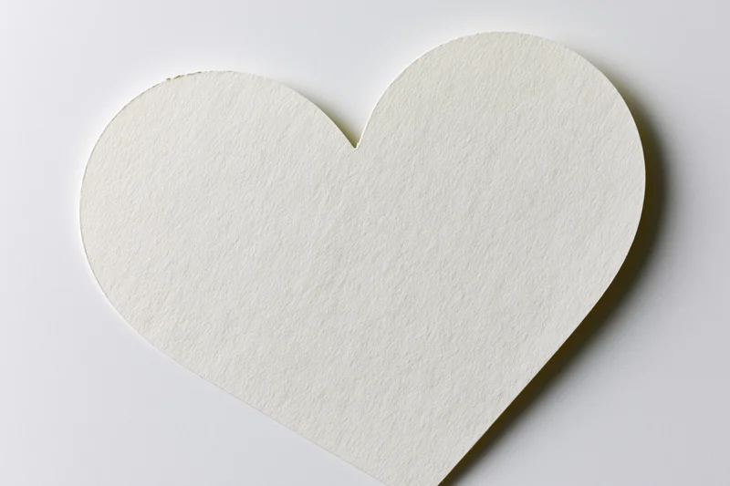 Heart-shaped paper cutout lying flat on white surface