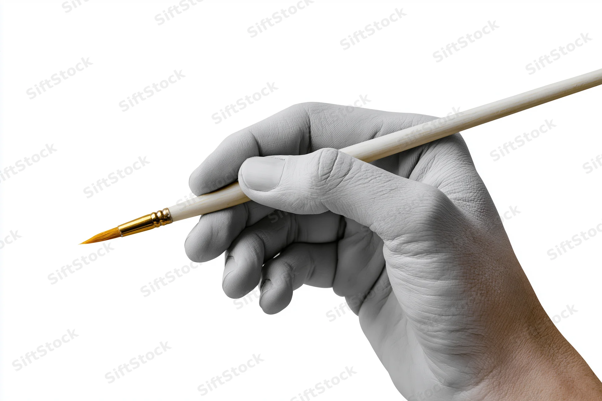 Hand holding a fine-tipped paintbrush against white background