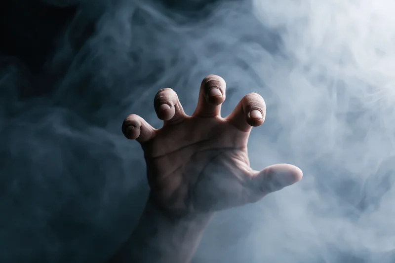 Hand reaching forward with fingers spread through swirling smoke