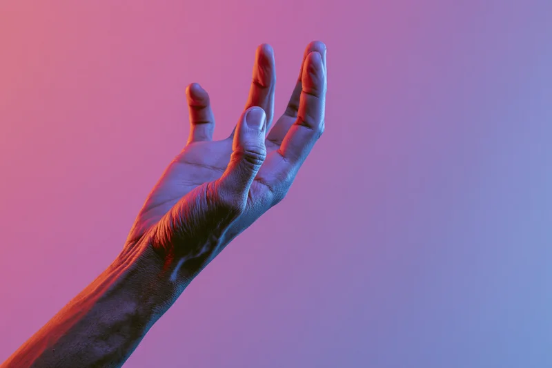 Hand reaching upward with fingers slightly curved against a pink and purple gradient background