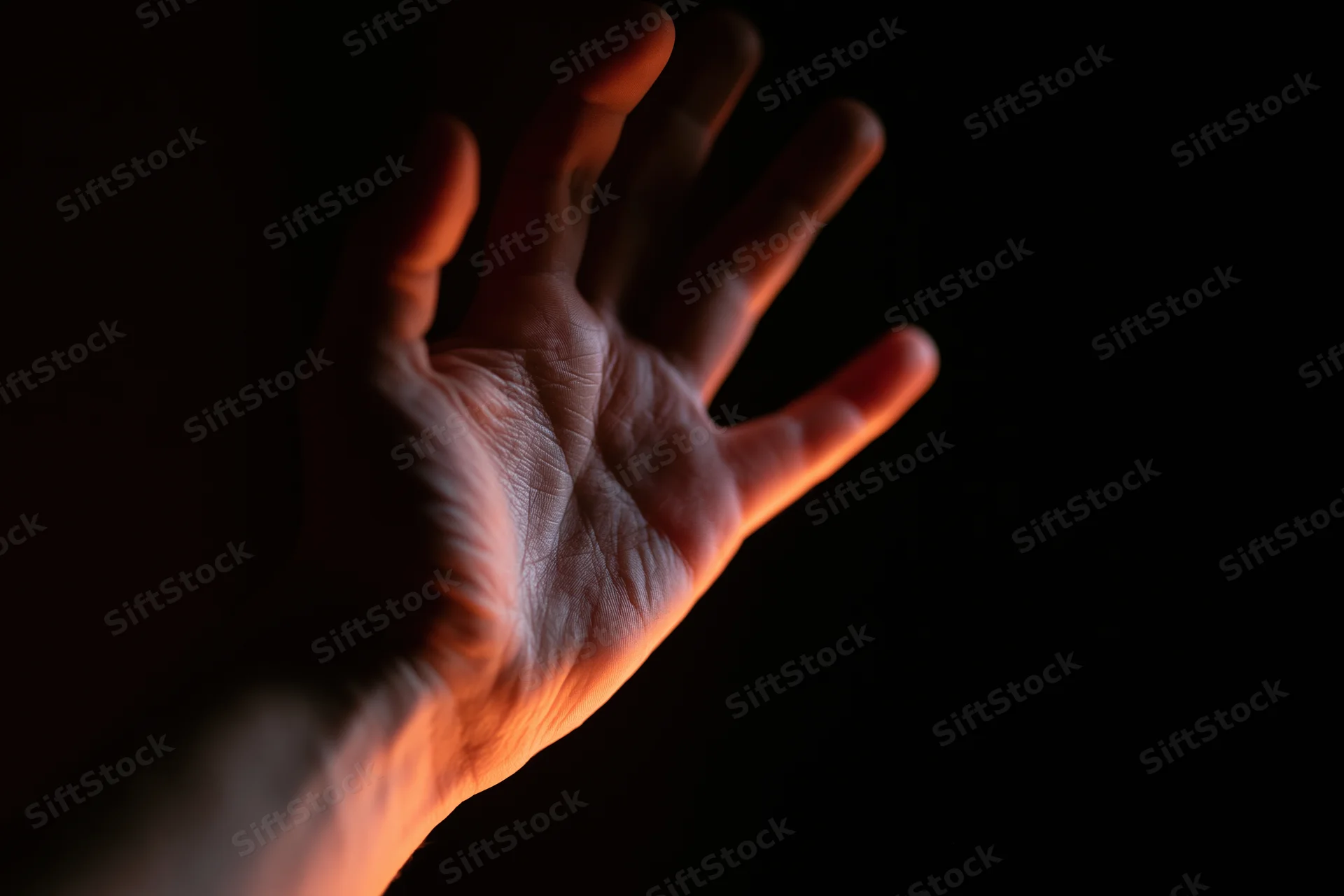 Hand reaching upward with fingers splayed against dark background