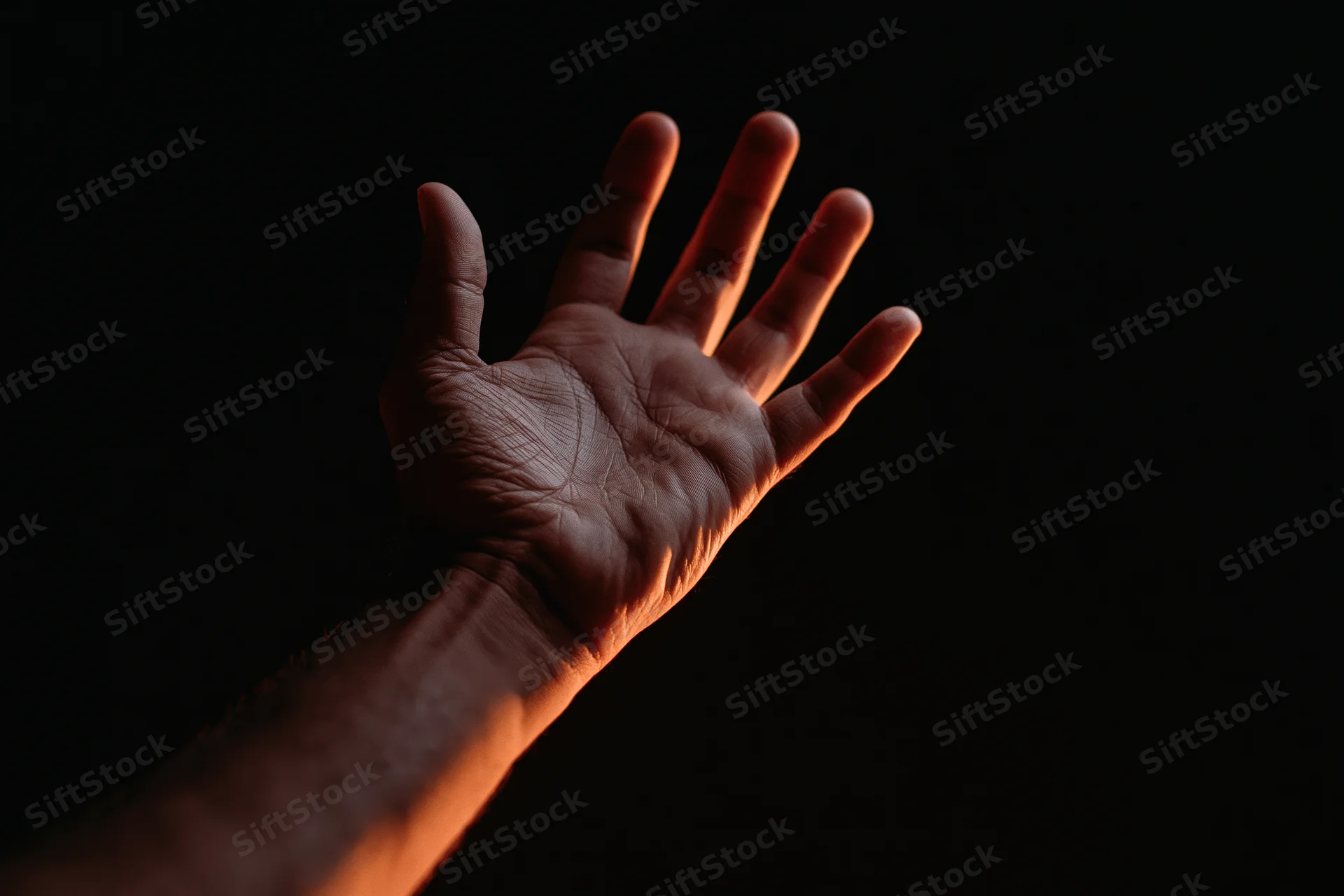 Hand reaching upward with fingers splayed against dark background