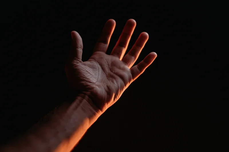 Hand reaching upward with fingers splayed against dark background