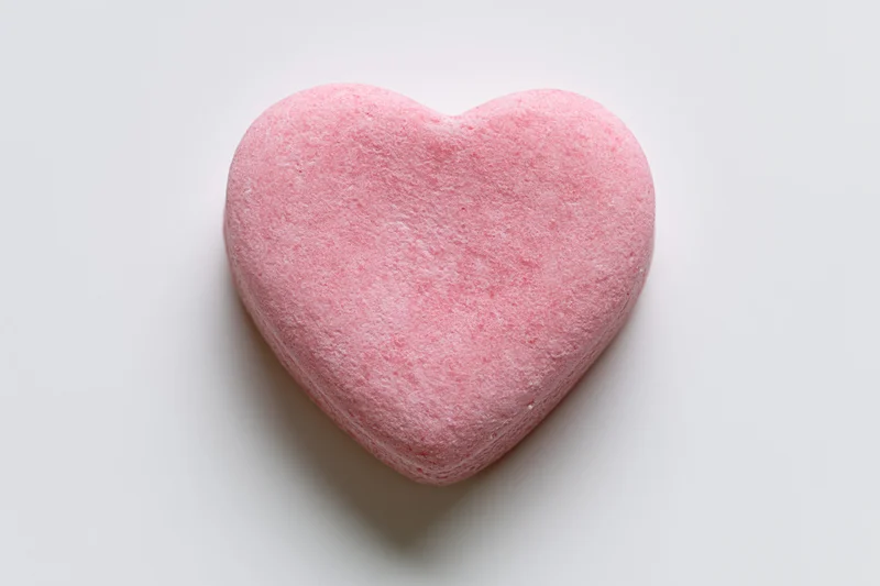Single pink heart-shaped candy conversation heart lying flat