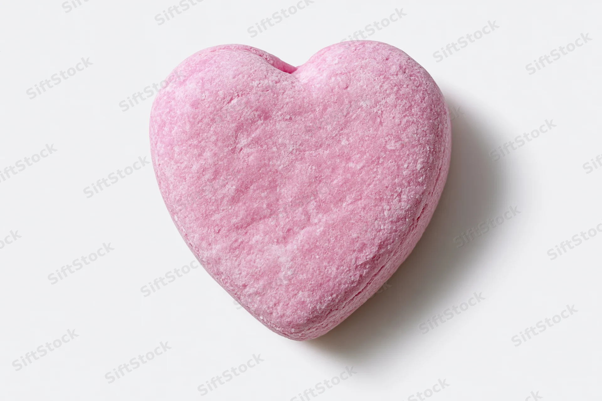 Pink heart-shaped candy lying flat on white surface
