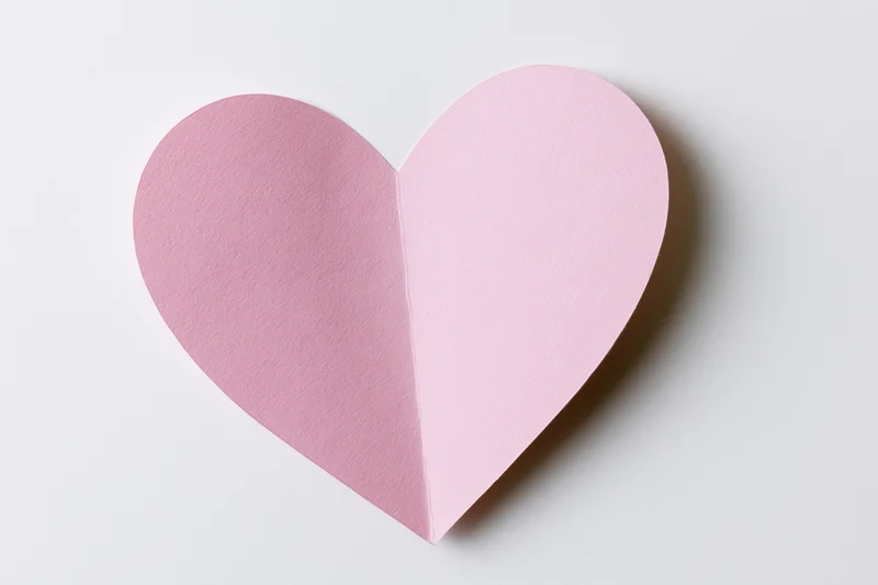 Pink paper heart cutout on white background