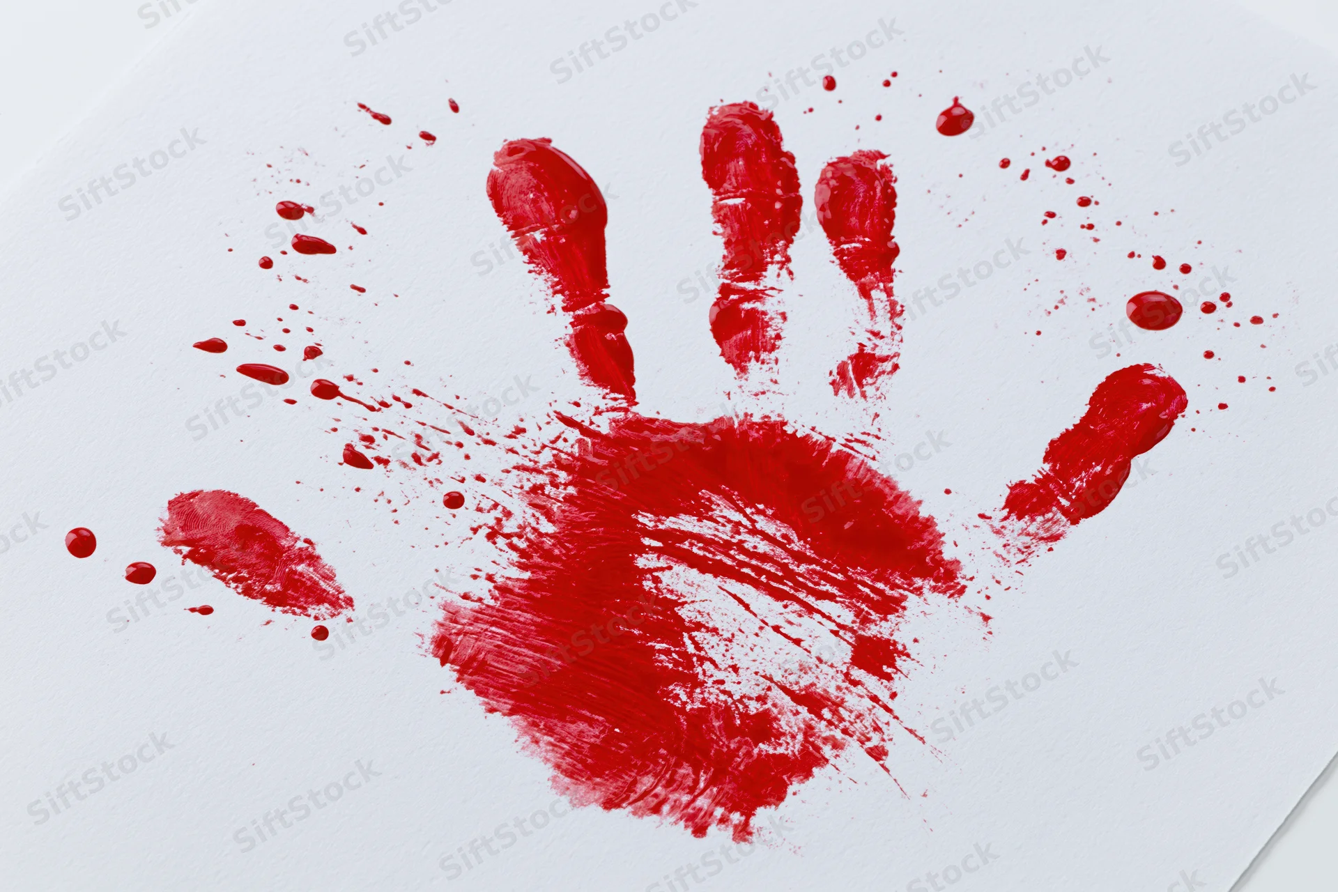 Red paint handprint on white paper with smudges and splatters