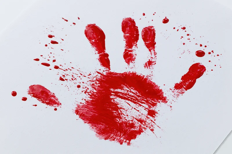 Red paint handprint on white paper with smudges and splatters