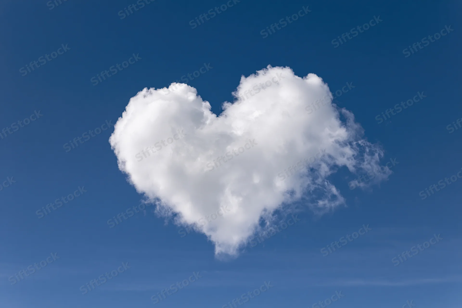Heart-shaped cloud floating in clear blue sky