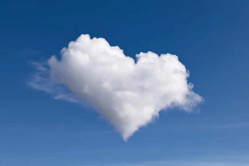 Heart-shaped cloud floating in clear blue sky