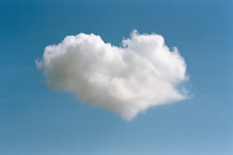 Heart-shaped cloud floating in a clear blue sky