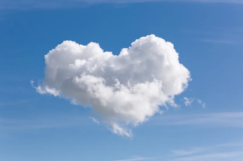 Heart-shaped cloud floating in a clear blue sky