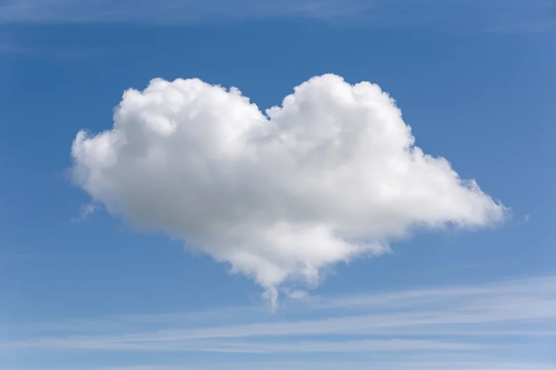 Heart-shaped cumulus cloud floating in a clear blue sky