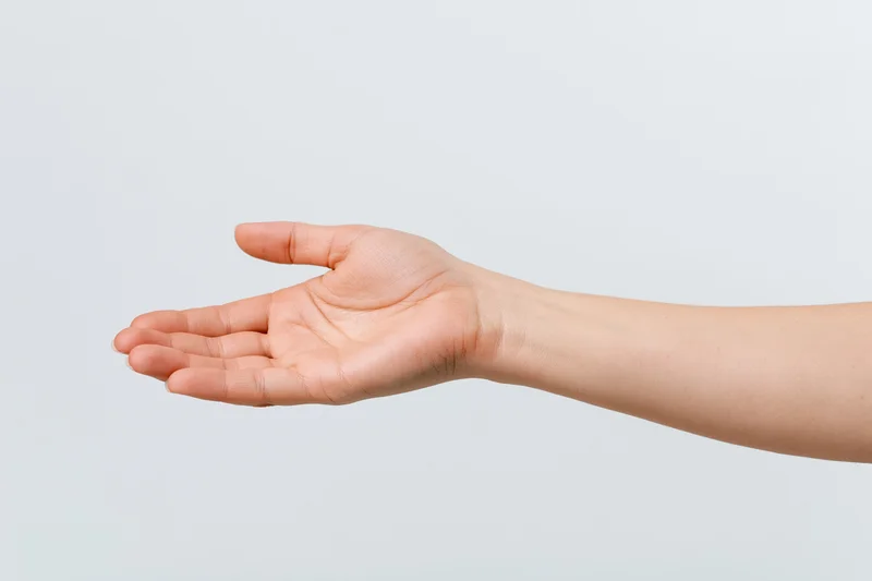 Woman's hand extended with open palm against plain background