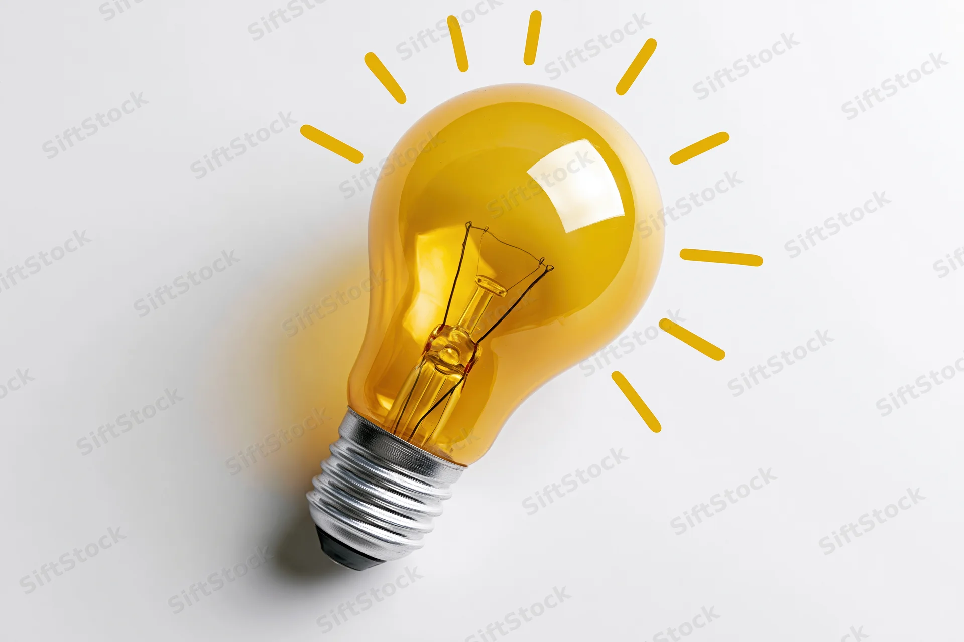 Yellow incandescent light bulb with glowing filament and radiating lines on white background