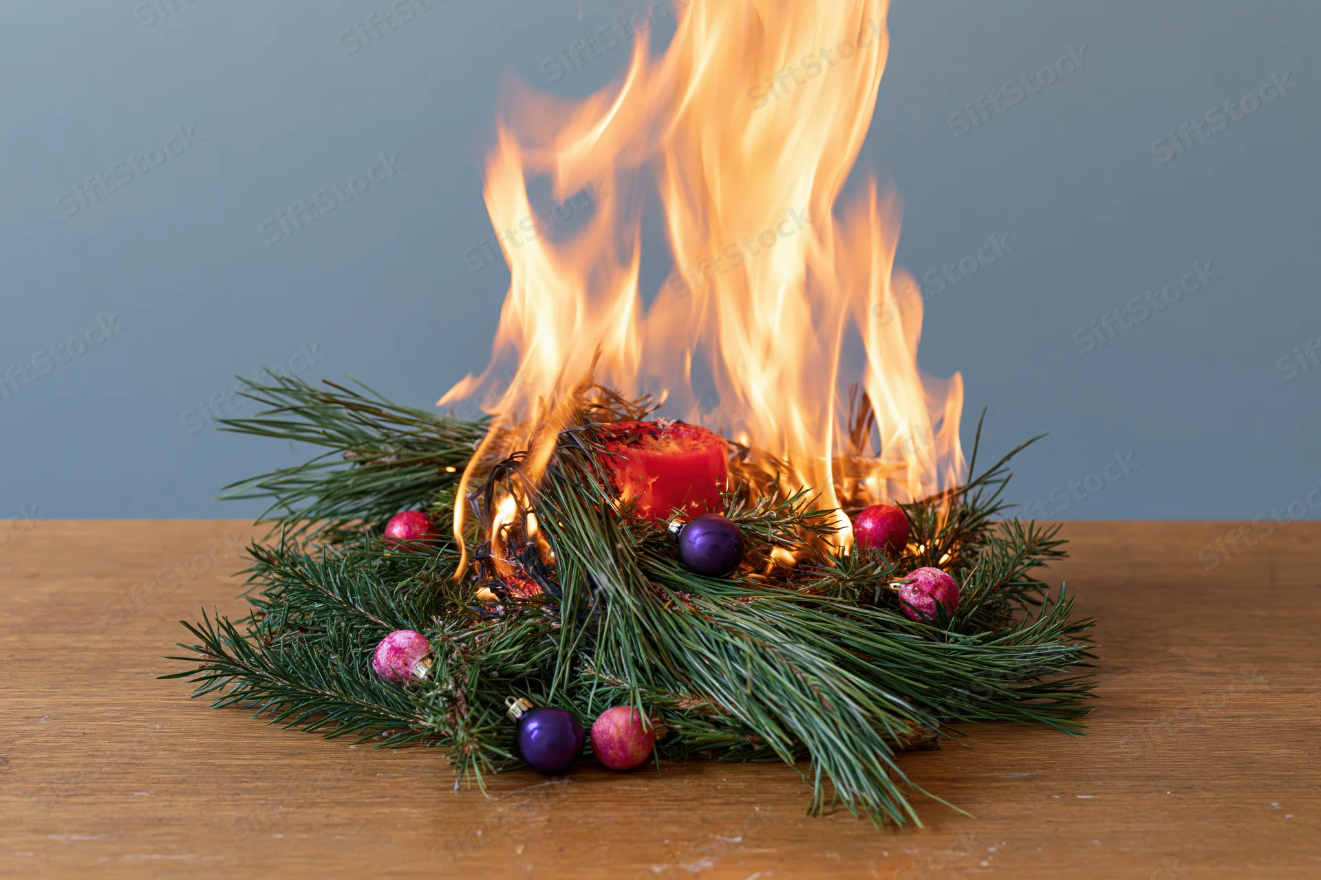 Burning christmas centerpiece with pine and ornaments on wooden table