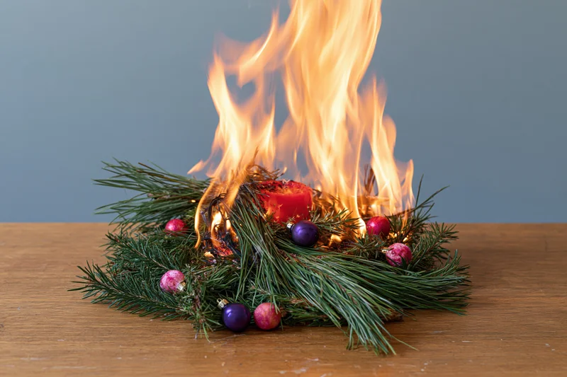 Burning christmas centerpiece with pine and ornaments on wooden table