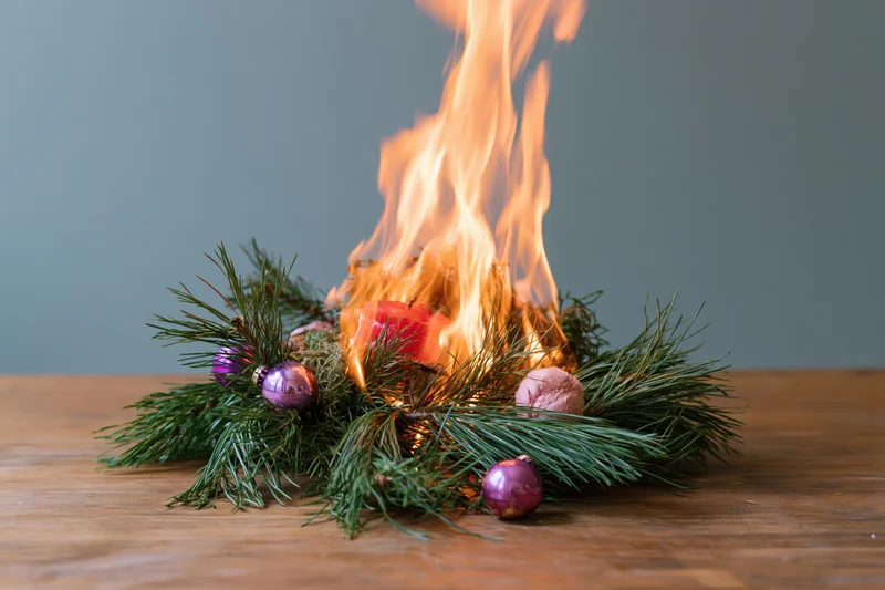 Burning christmas centerpiece with pine and ornaments on wooden table