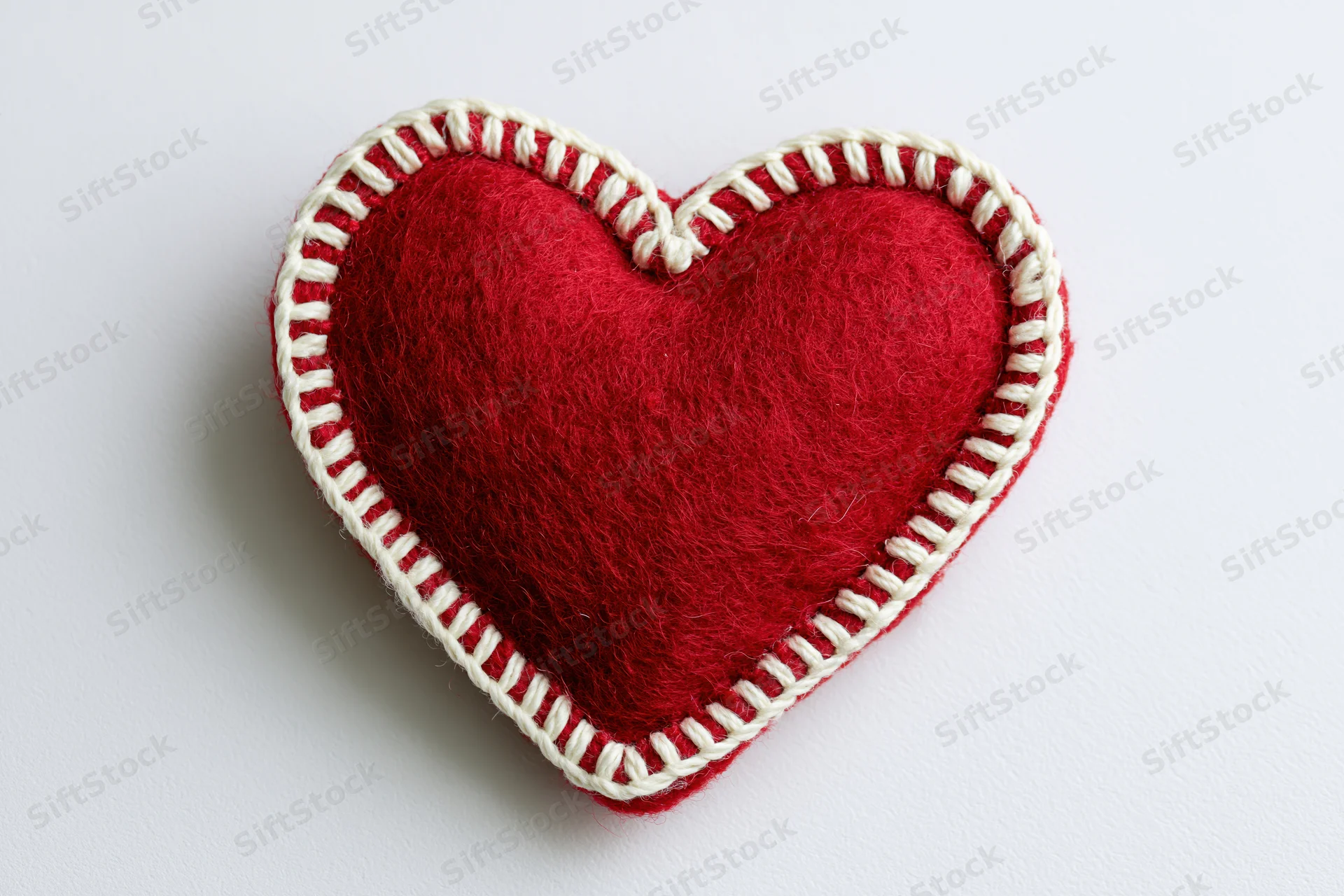 Handmade red felt heart with white blanket stitch on white background