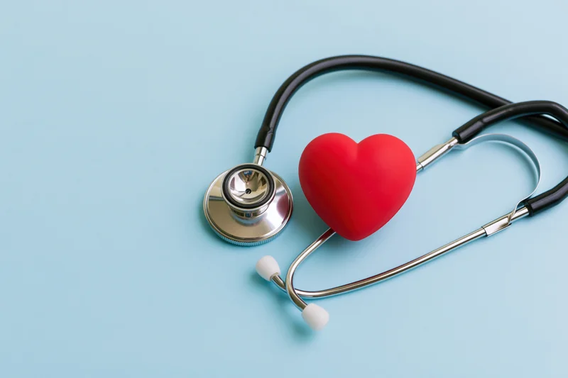Stethoscope with red heart toy on blue background