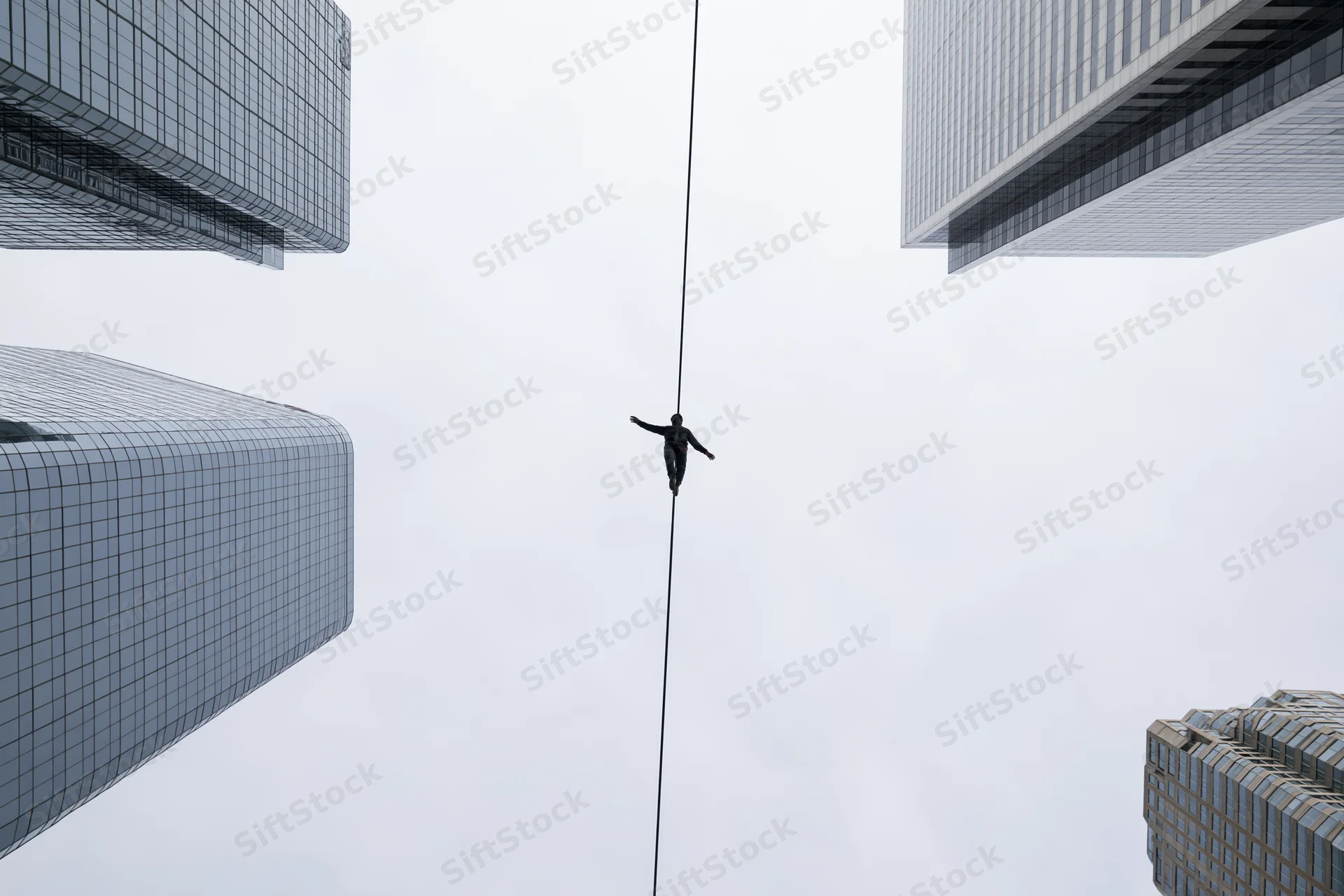 Tightrope walker balancing on a high wire between skyscrapers in an urban skyline