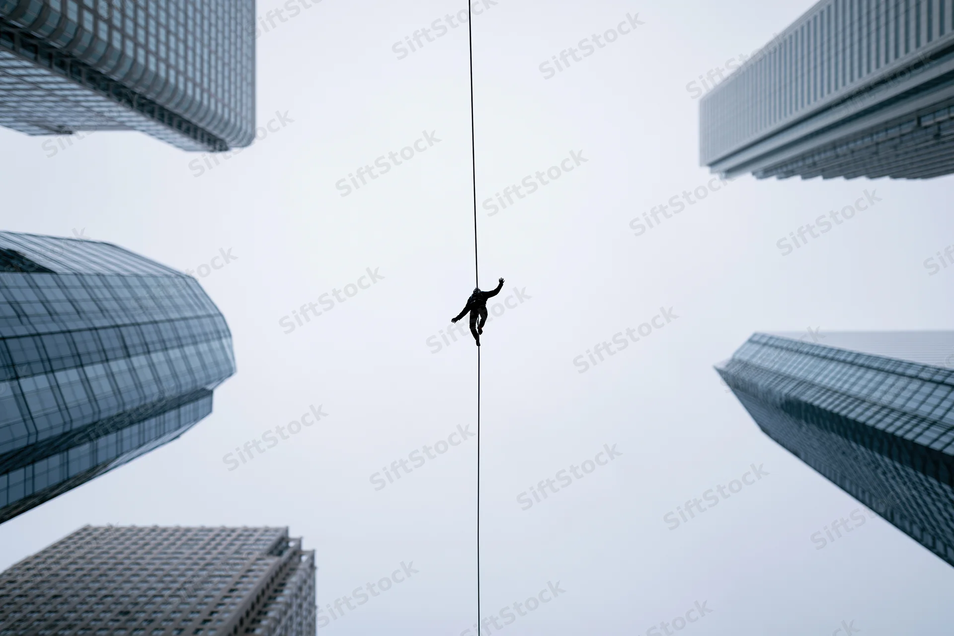 Tightrope walker balancing on a high wire between skyscrapers in a modern city
