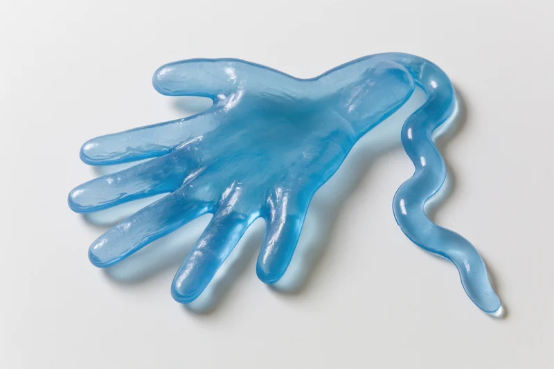 Translucent blue rubber hand toy lying flat on white surface