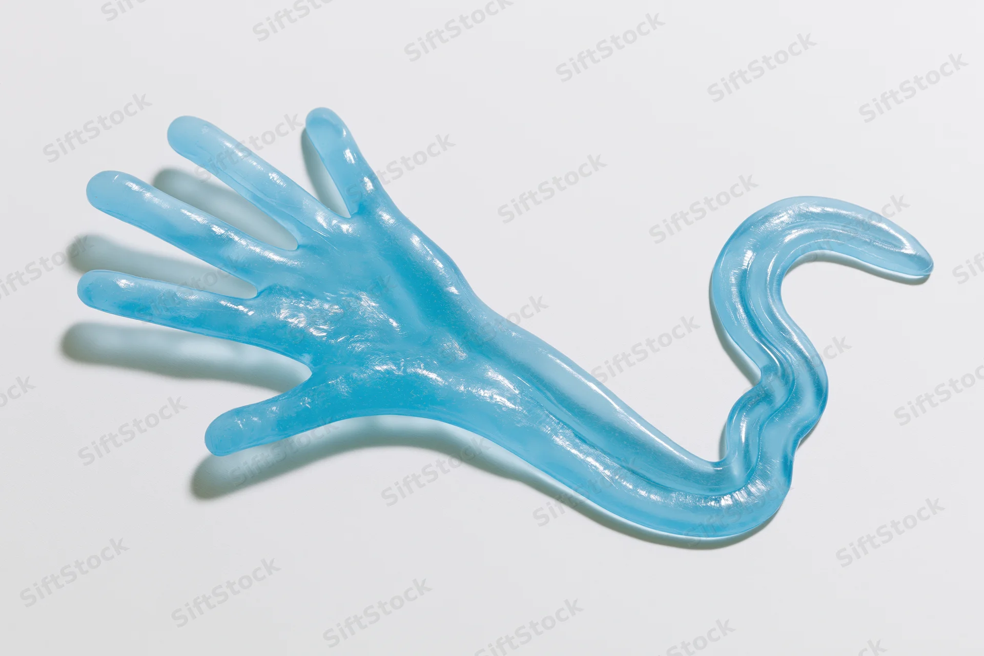 Translucent blue rubber hand toy with elongated tail lying flat on white surface