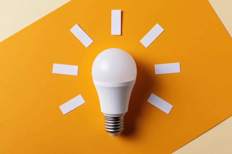 White led lightbulb on orange paper with white rectangles arranged in sunburst pattern