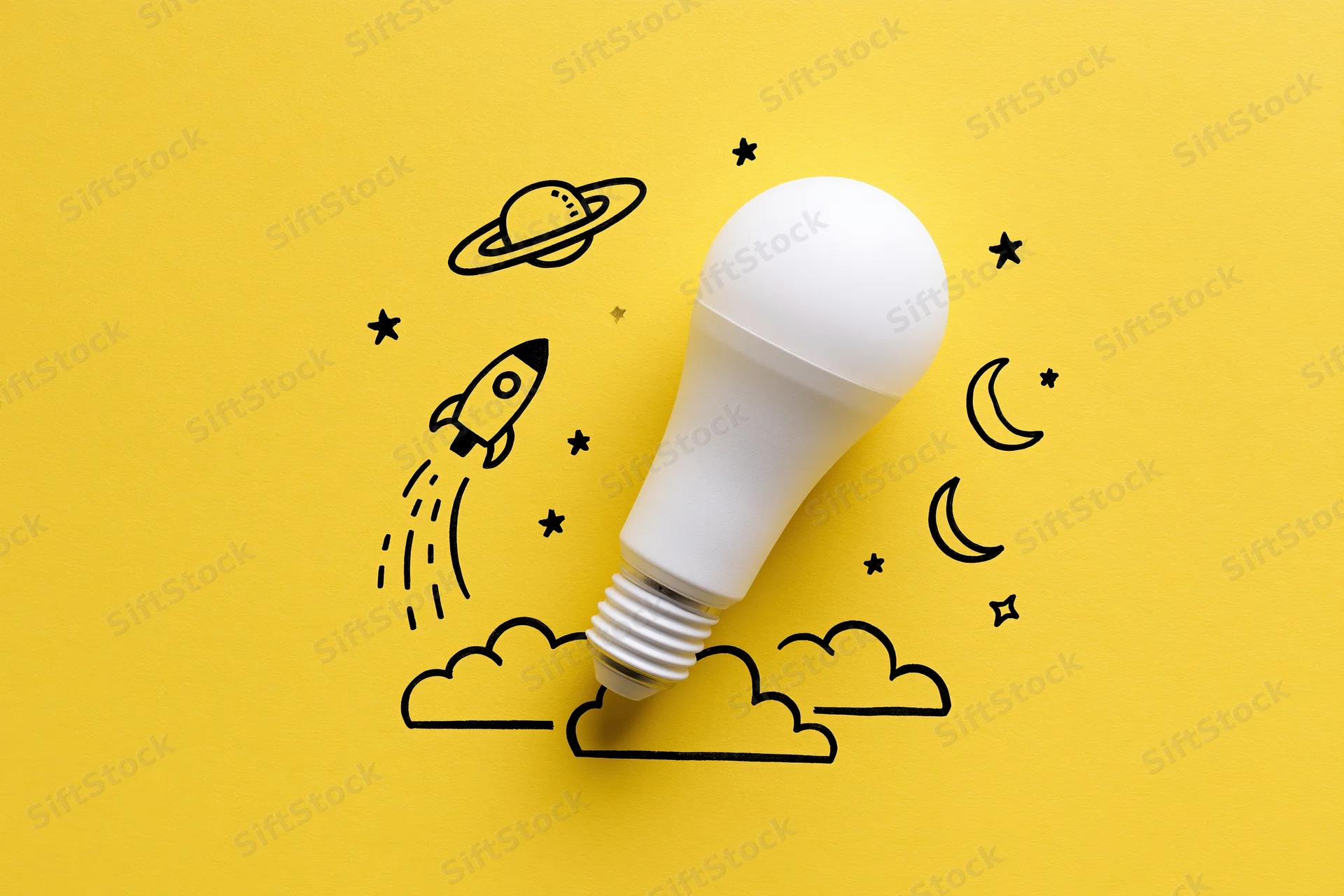 White led lightbulb on yellow paper with hand-drawn space and rocket illustration