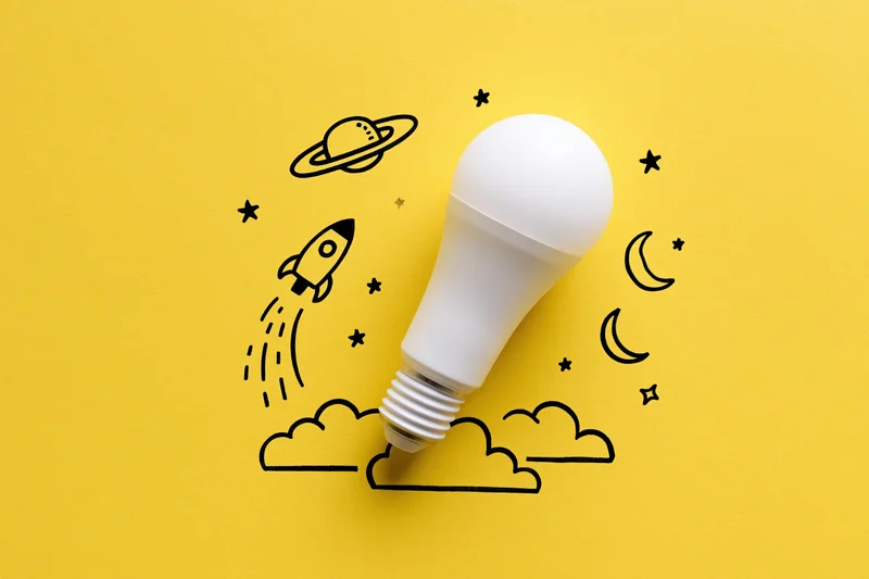 White led lightbulb on yellow paper with hand-drawn space and rocket illustration