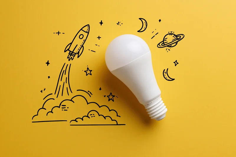 White led lightbulb on yellow background with rocket and space doodles