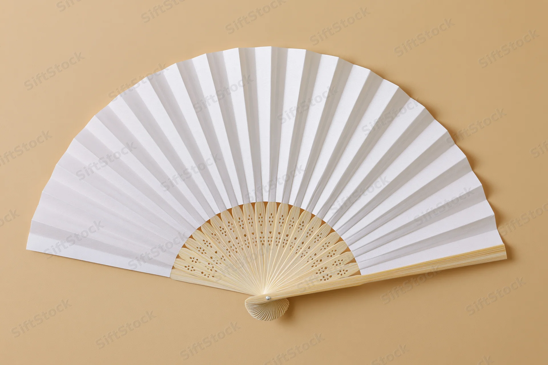 White paper hand fan fully opened and laid flat on beige background