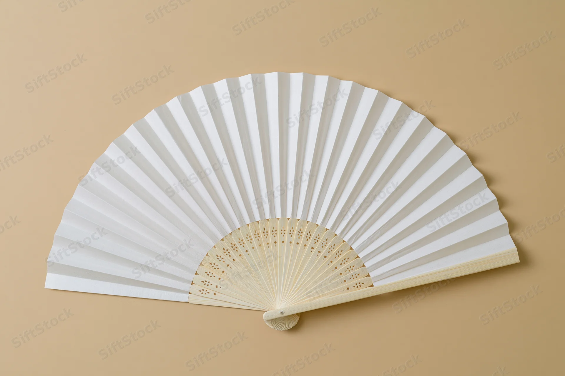 White paper hand fan fully opened and laid flat on beige background
