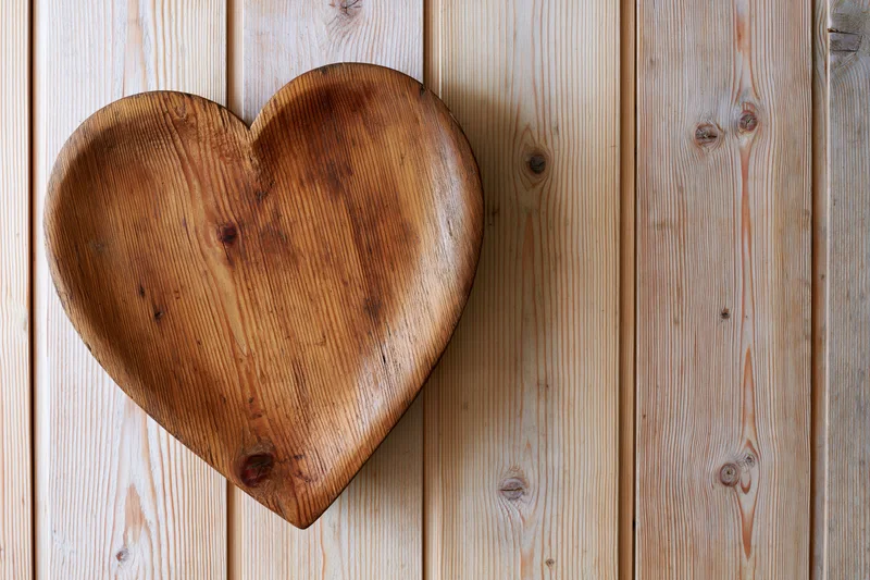 Heart-shaped wooden tray resting against vertical pine planks