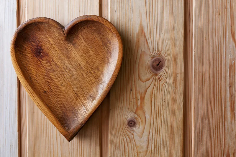 Heart-shaped wooden tray resting on vertical pine paneling