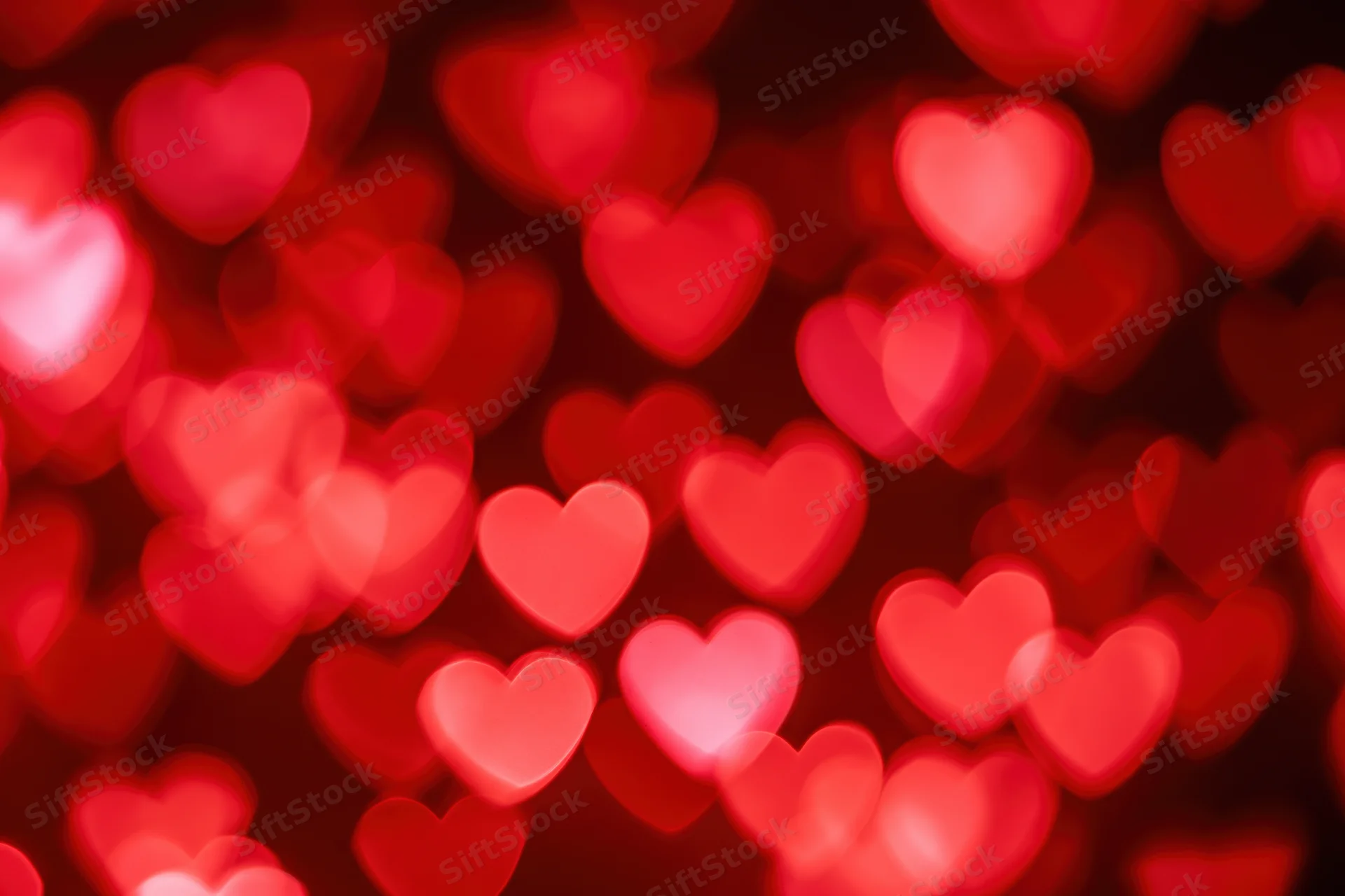 Soft out-of-focus heart shapes glowing in red and pink bokeh background