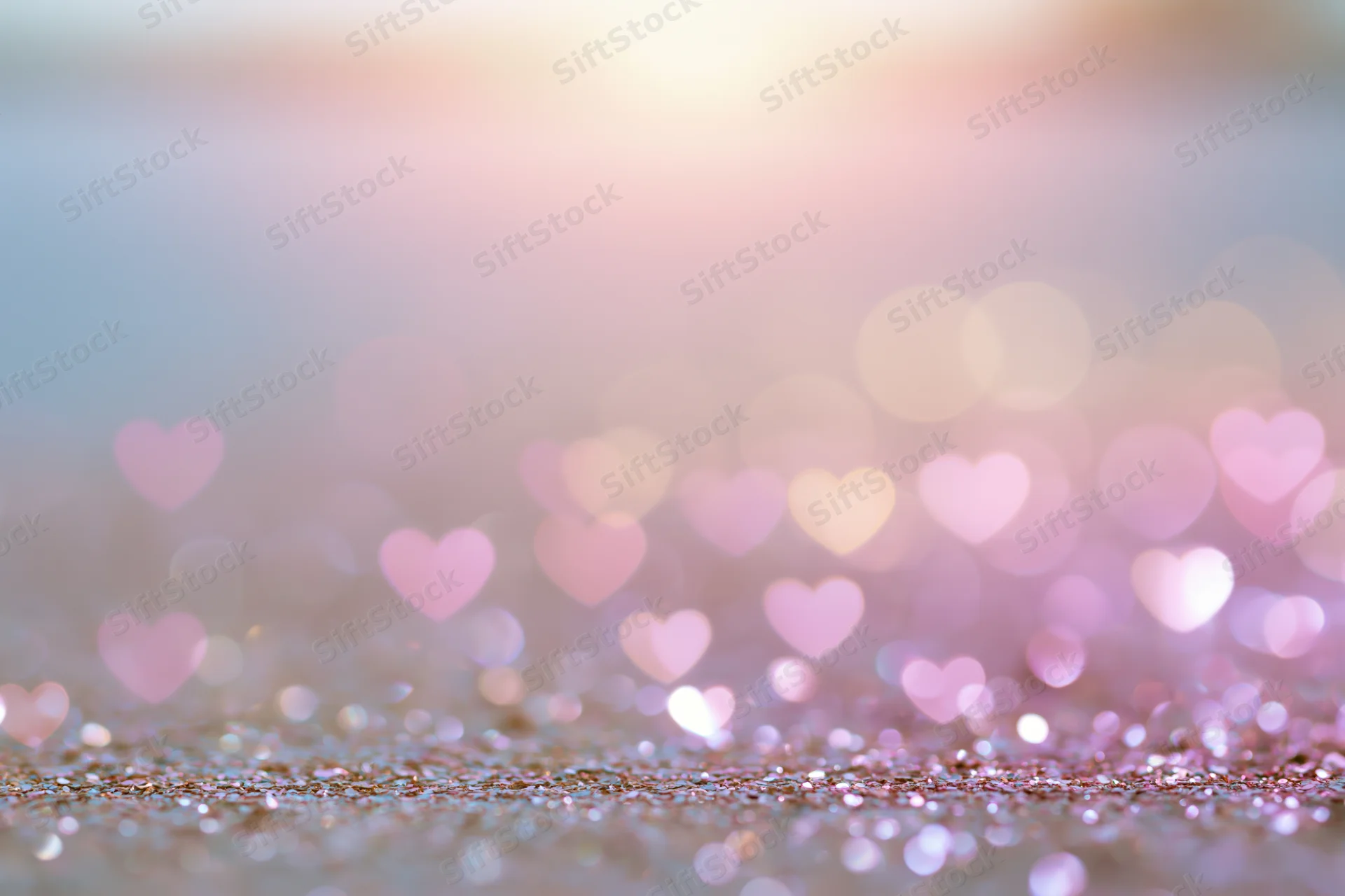 Heart-shaped bokeh lights over glittery surface with soft pink glow