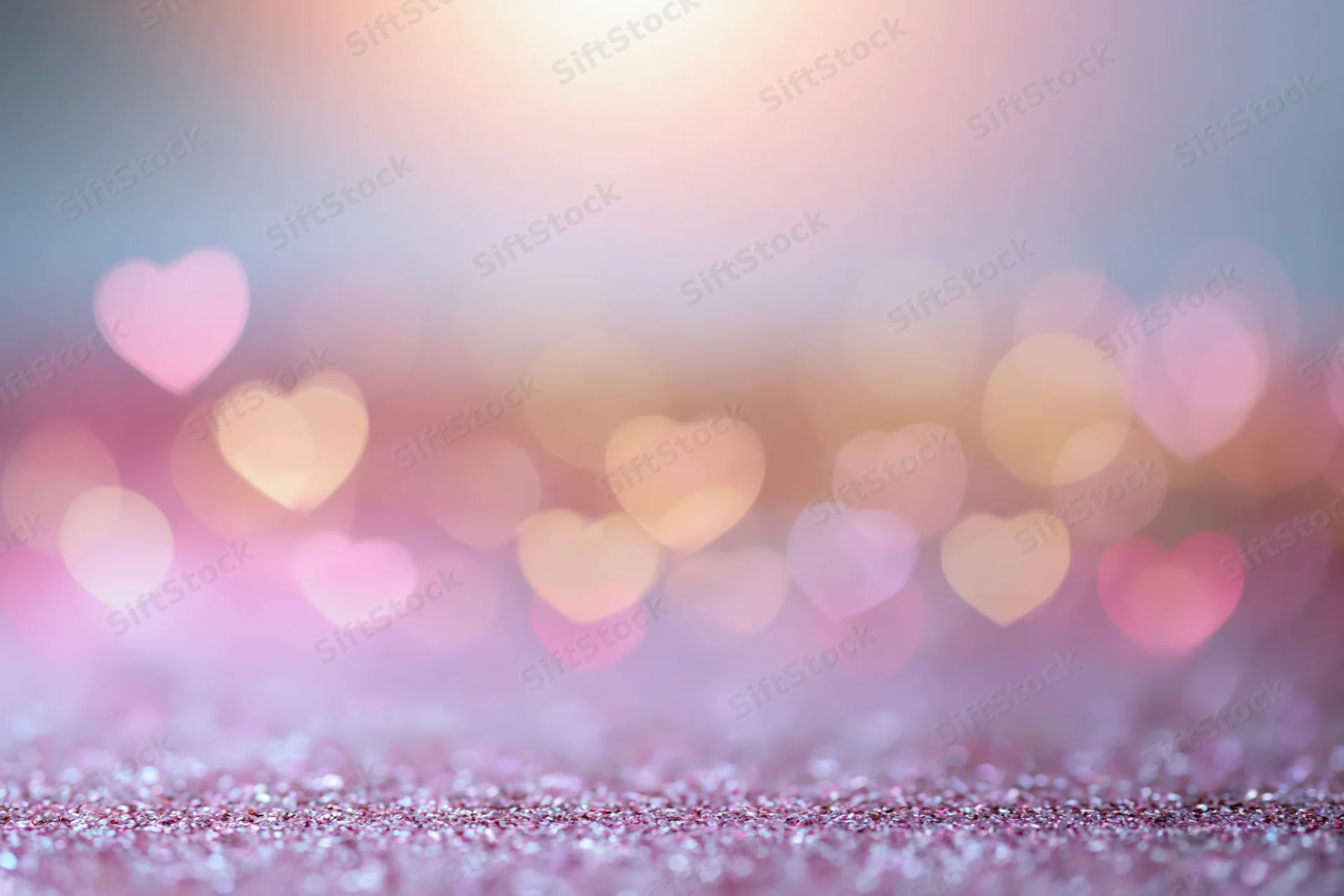 Heart-shaped bokeh lights over glittery pink surface with soft focus background