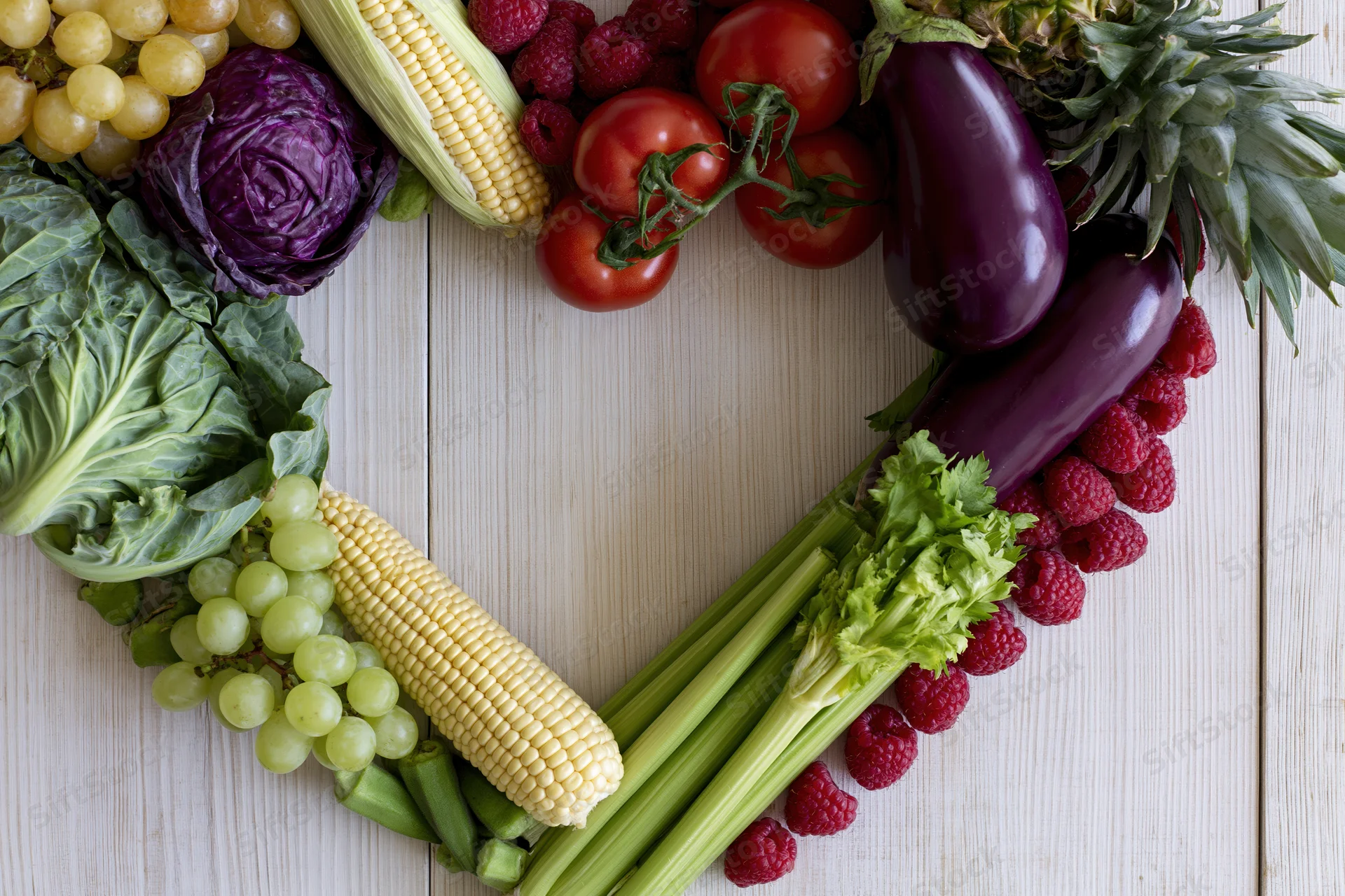 Heart-shaped arrangement of fresh fruits and vegetables on wooden surface