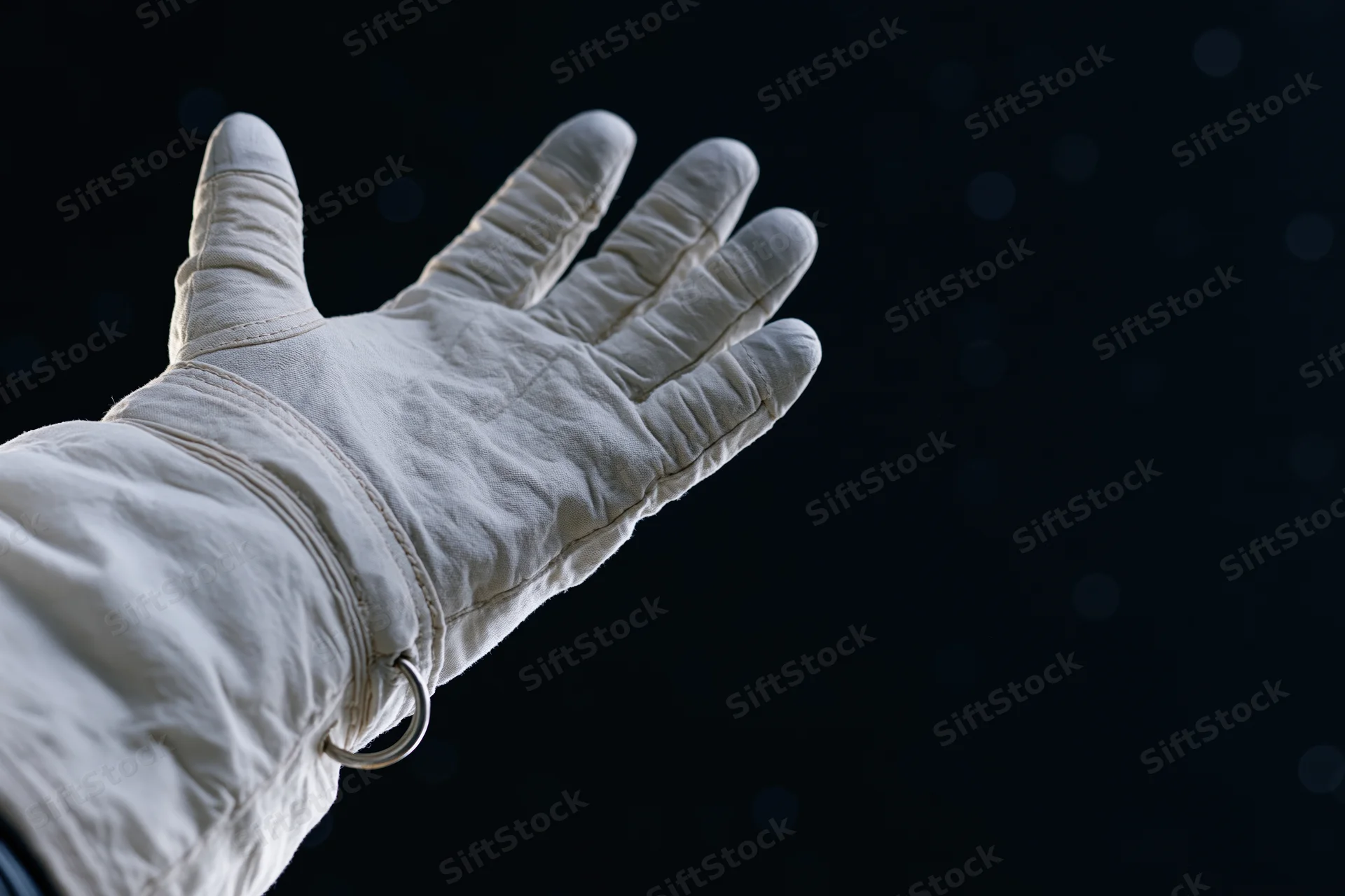 Astronaut's gloved hand extended palm-up against dark space background