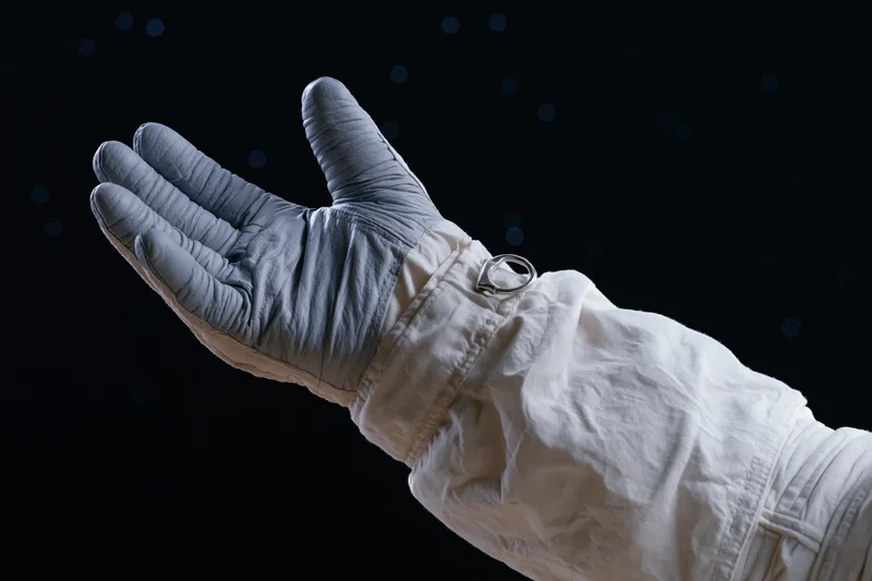 Astronaut's gloved hand extended palm-up against starry space background