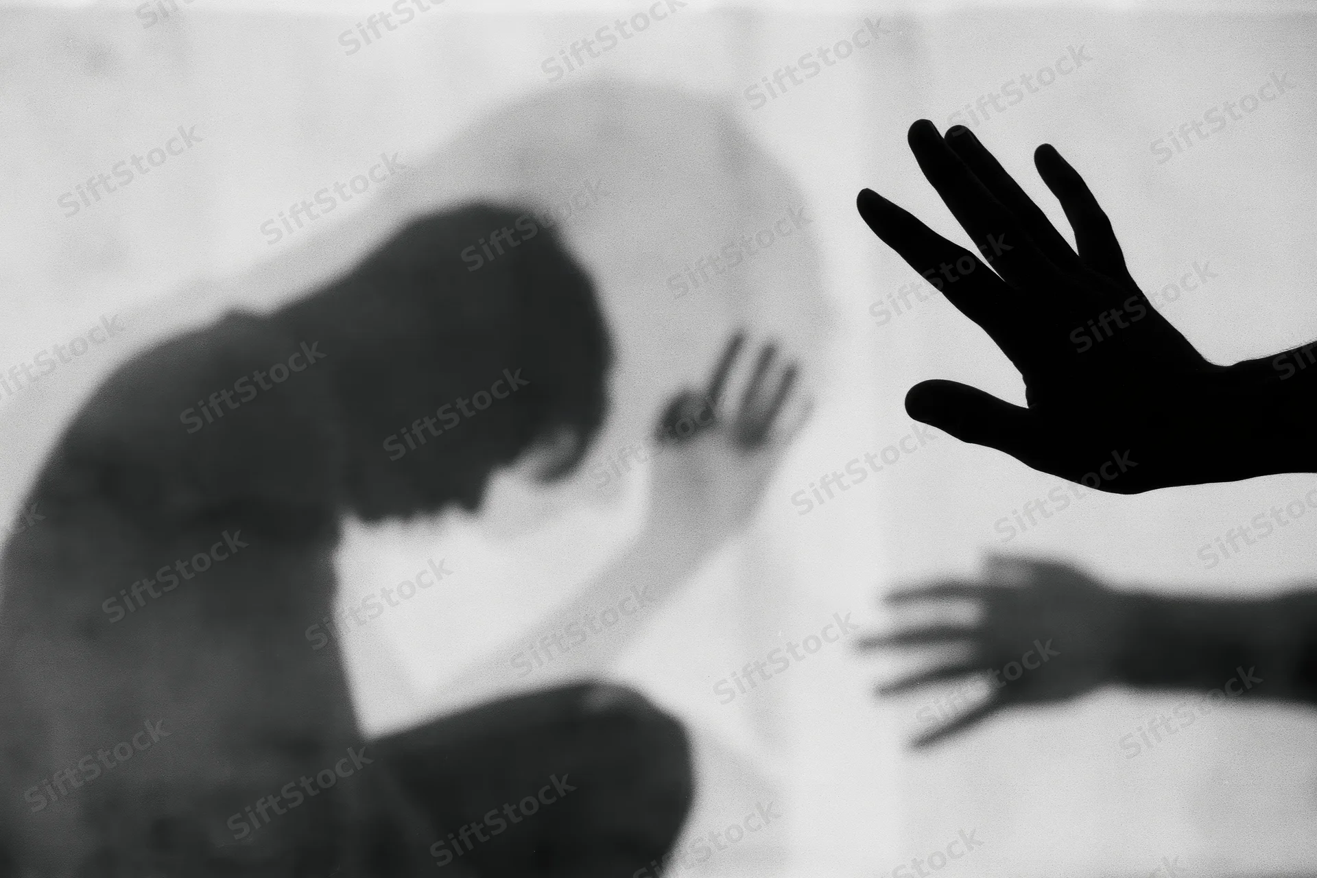 Silhouette of a distressed person with hands reaching through glass in a double exposure effect