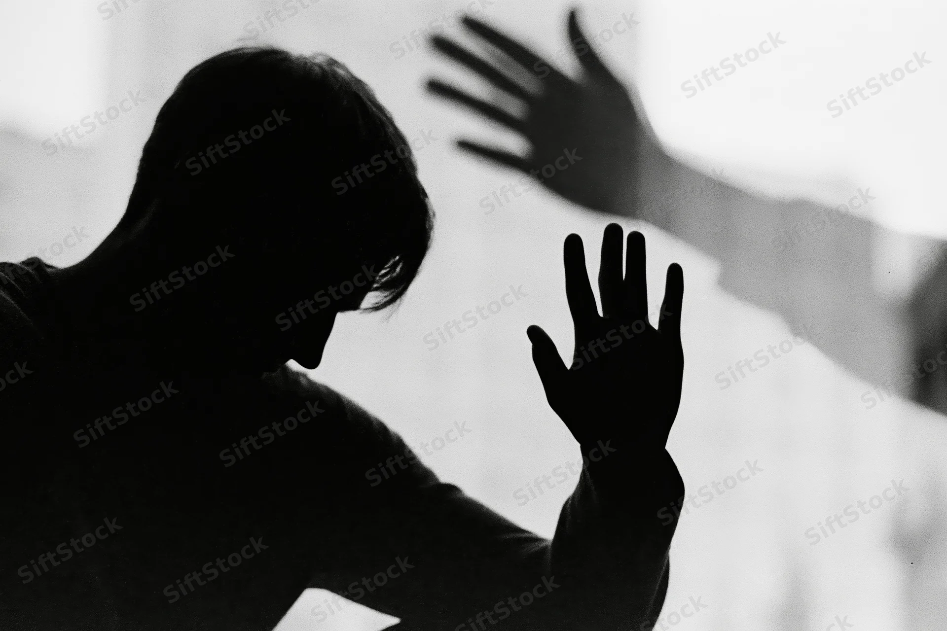 Silhouette of a distressed man reaching out with hand against a bright background