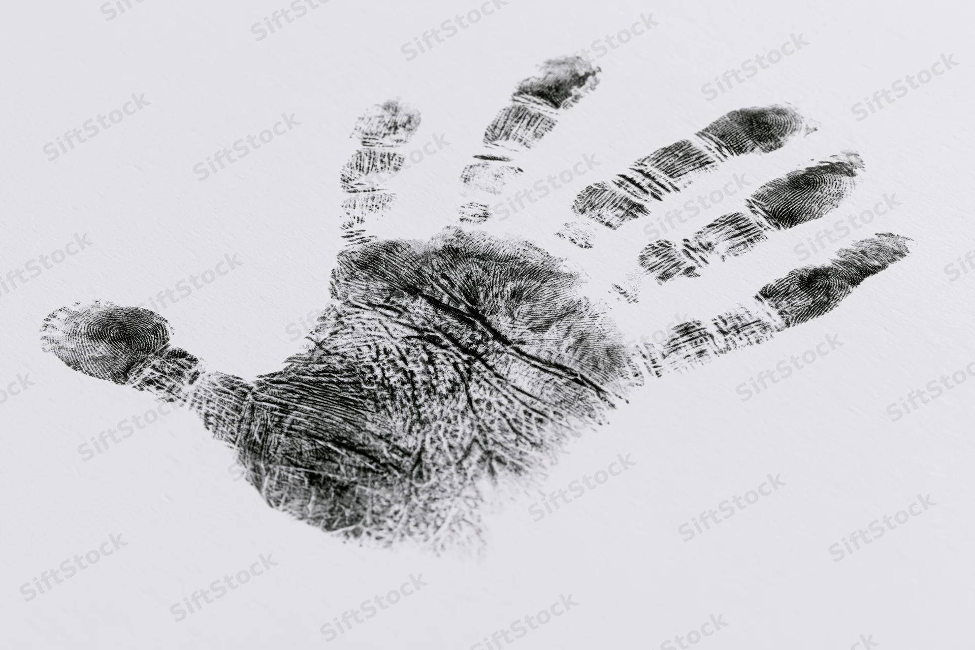 Black ink handprint of a child pressed onto white paper