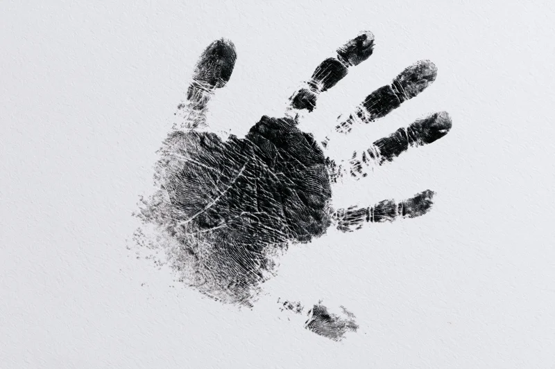 Black ink handprint of a child pressed onto white paper