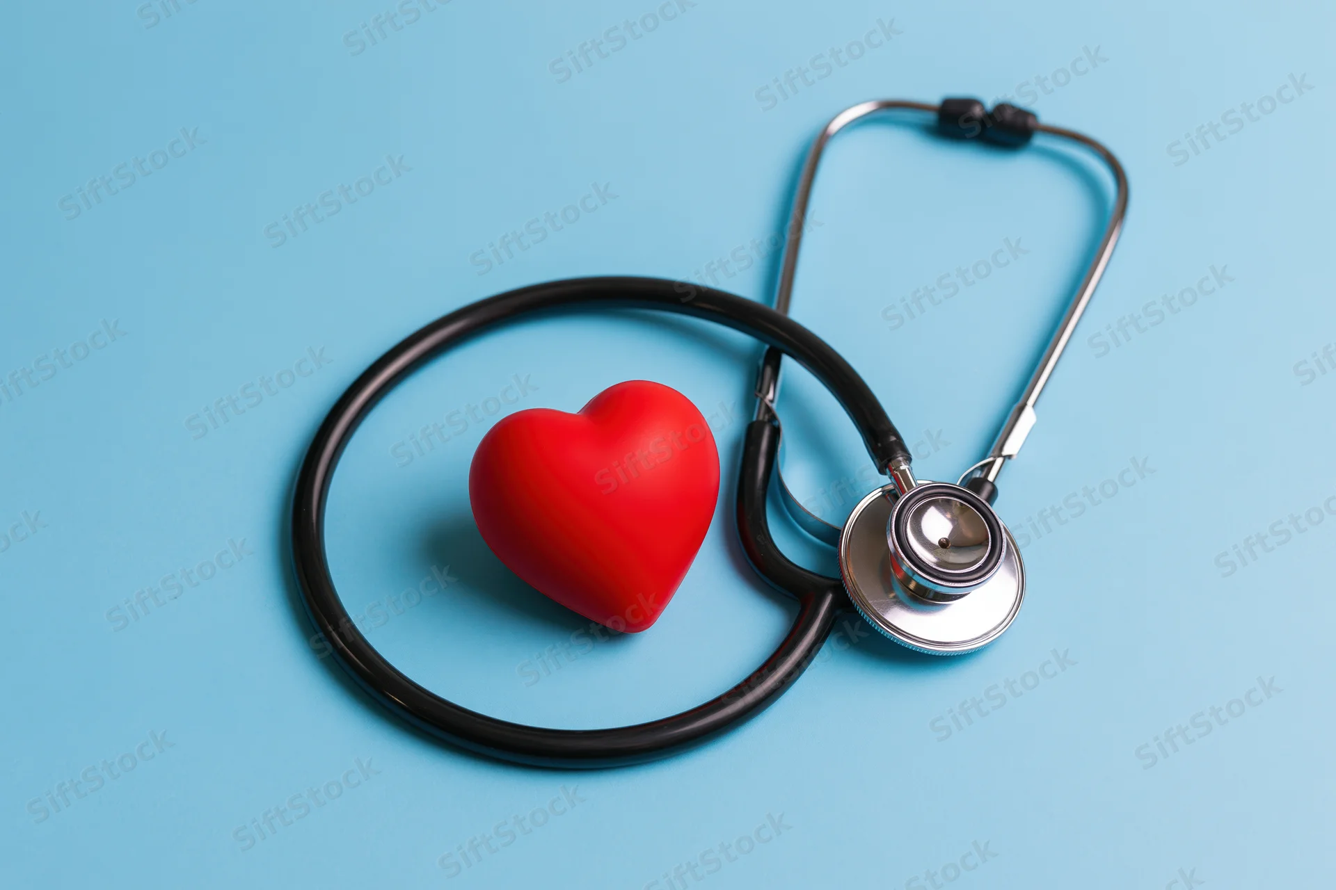 Stethoscope coiled around a red heart symbol on a blue background
