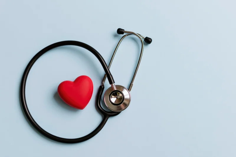 Stethoscope with red heart symbol on light blue background